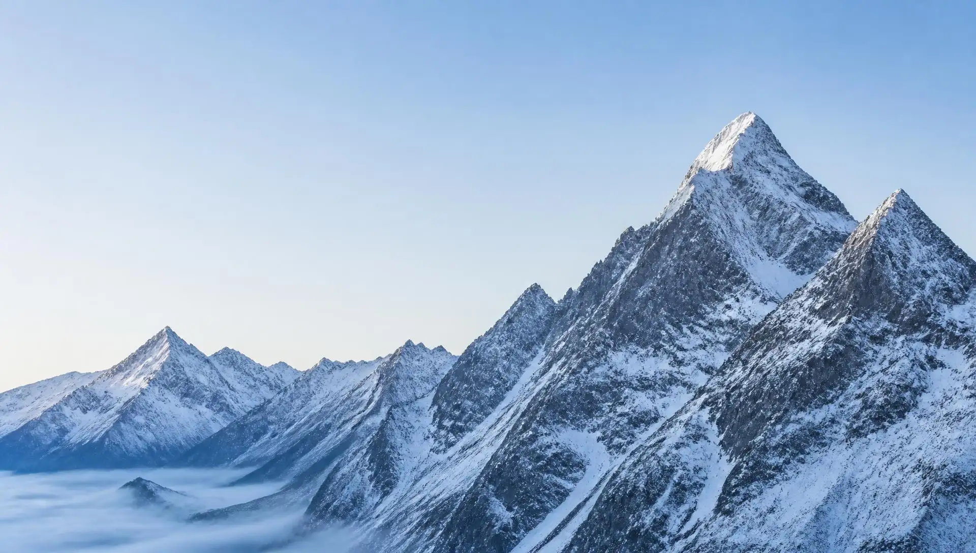 Snow-covered Swiss alpine peaks at dawn under a pale sky